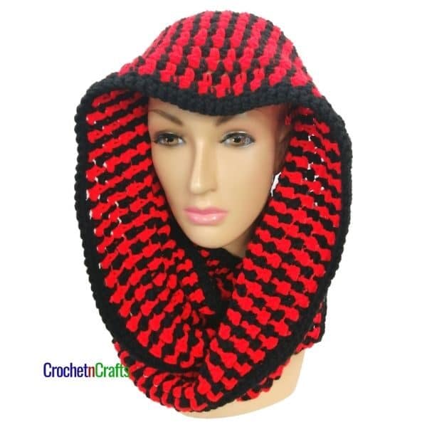 A two tone infinity crochet scarf shown wrapped around the head for a hooded cowl.