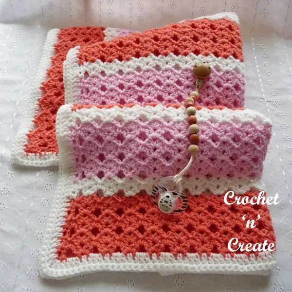 Crocheted baby blanket shown in a striped shell stitch.