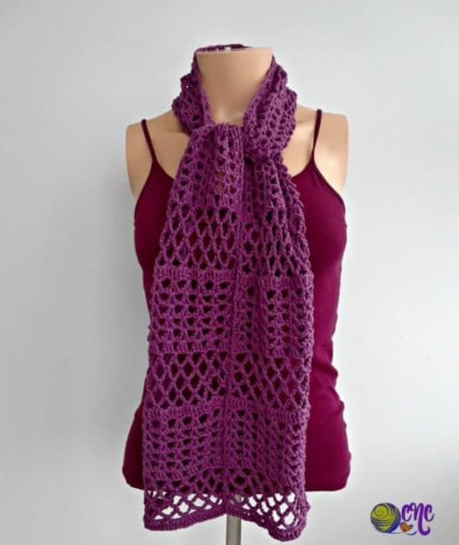 A lacy summer scarf tied in a knot around a mannequins neck. The crochet scarf can be worn in other ways as you like.