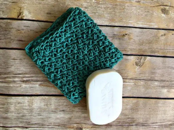 crochet washcloth folded up beside a bar of soap.