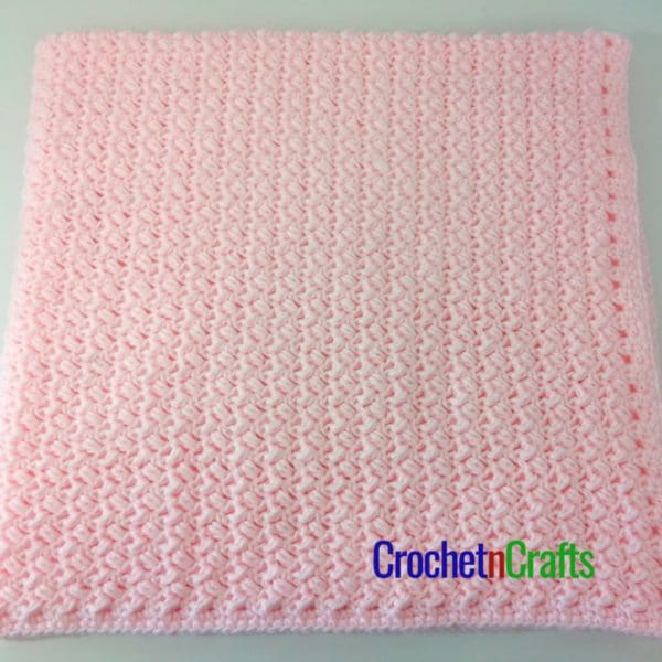 A crocheted baby blanket folded up.
