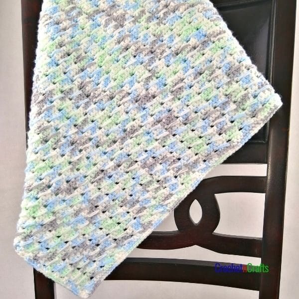 A cozy textured crochet blanket draped over the back of a chair.