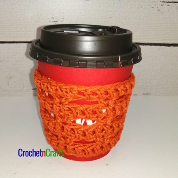 The crochet cup cozy pattern is shown take-out coffee cup.