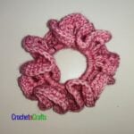 Crochet hair scrunchie shown in pink yarn called Stonewashed by Scheepjes.