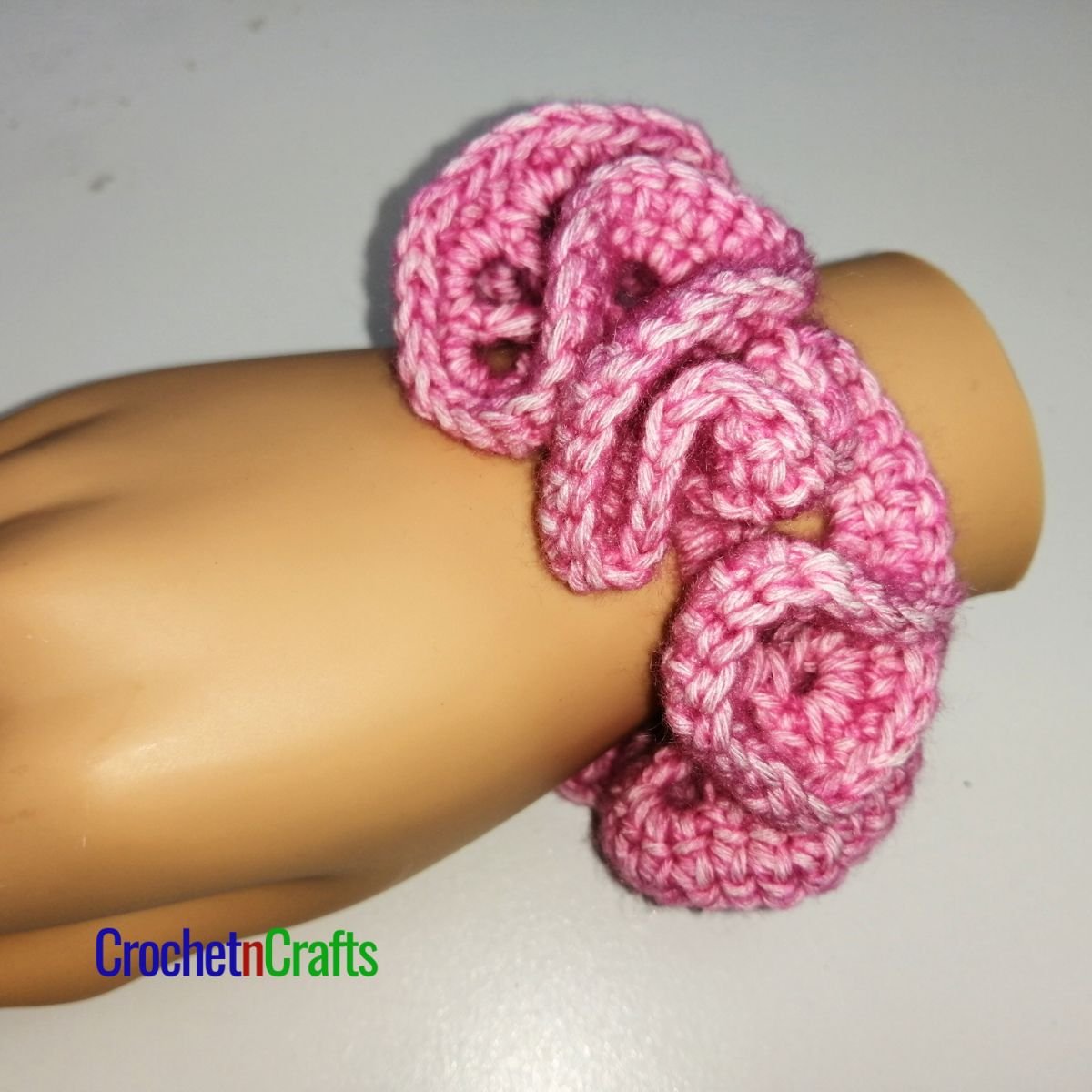 Crochet hair scrunchie shown in pink yarn called Stonewashed by Scheepjes.