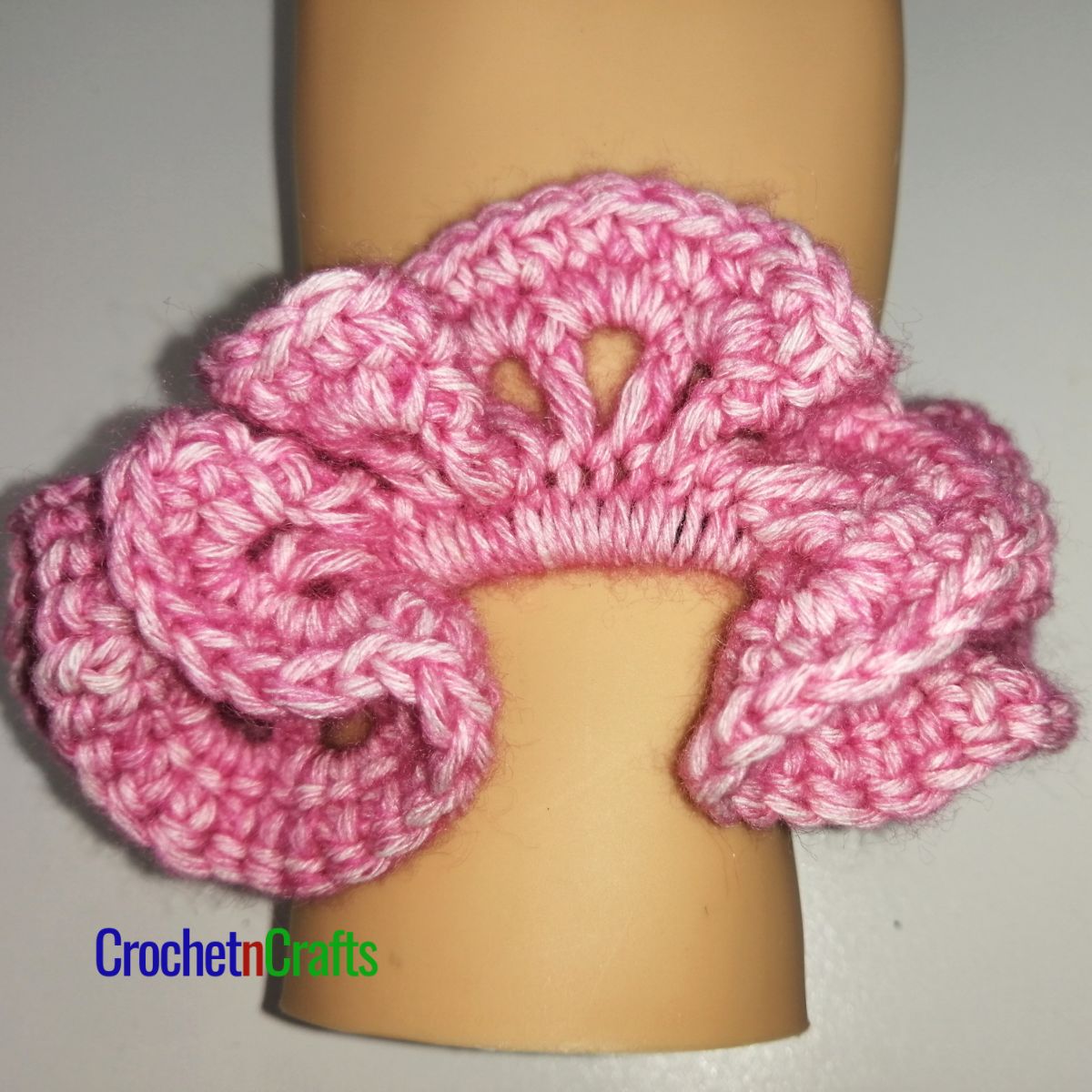 Crochet hair scrunchie shown in pink yarn called Stonewashed by Scheepjes.