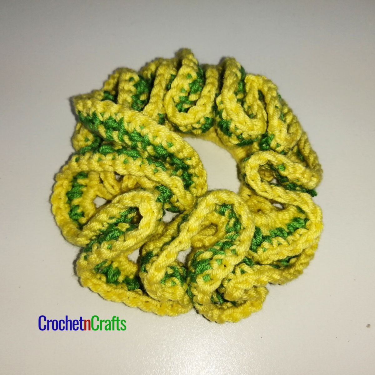 Crochet hair scrunchie shown in yellow and a stripe of green.