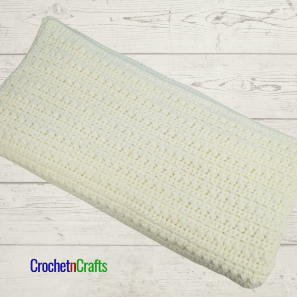 Textured crochet baby blanket shown in white - folded up.