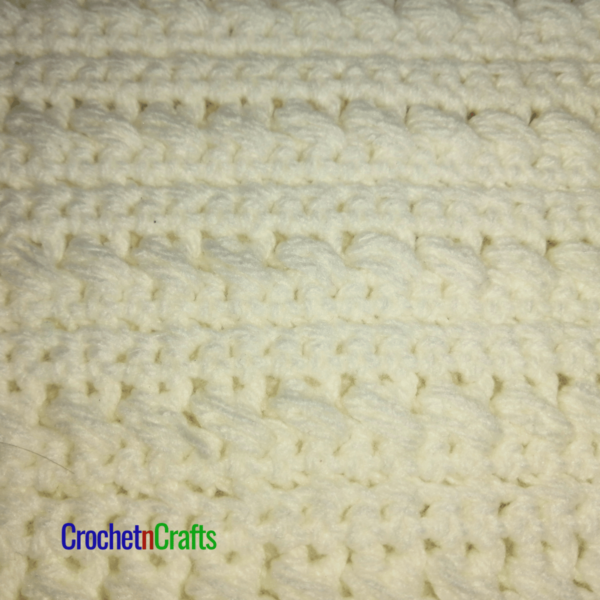 Textured crochet baby blanket shown in white - closeup.