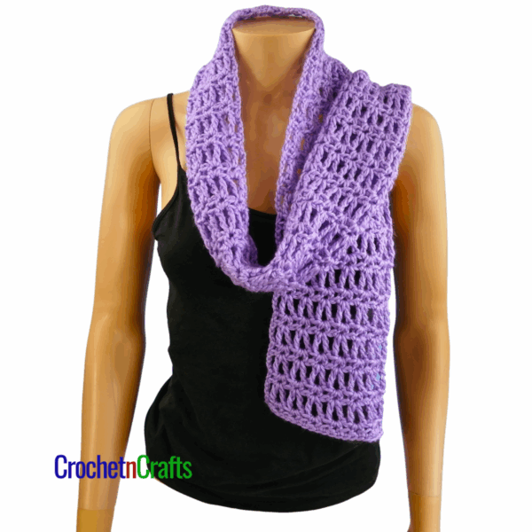 Crocheted scarf shown on a mannequin. Loosely draped over the shoulder - front view.