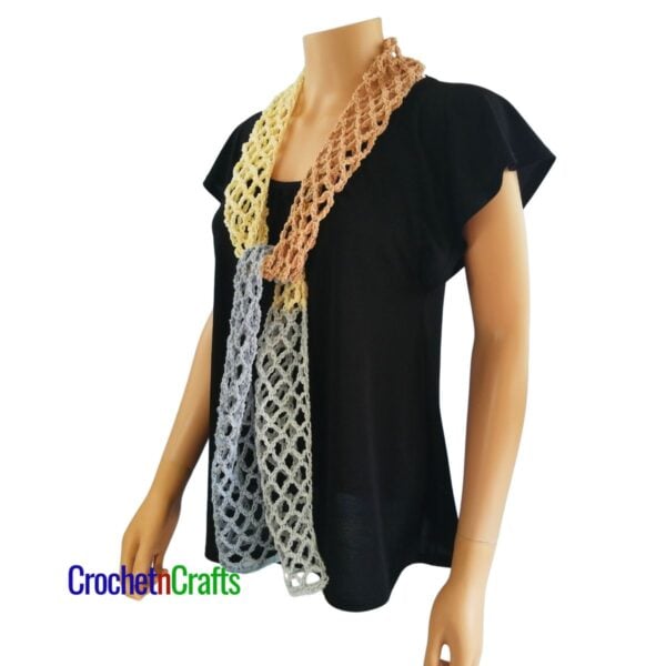 Crocheted mesh scarf pattern shown on a mannequin - tied at the front - side view.