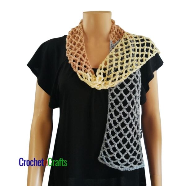 Crocheted mesh scarf pattern shown on a mannequin - draped over one shoulder.
