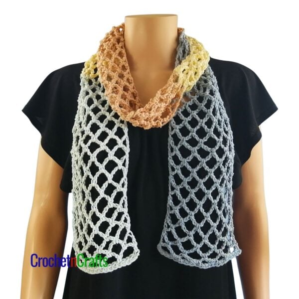 Crocheted mesh scarf pattern shown on a mannequin - wrapped around the neck.