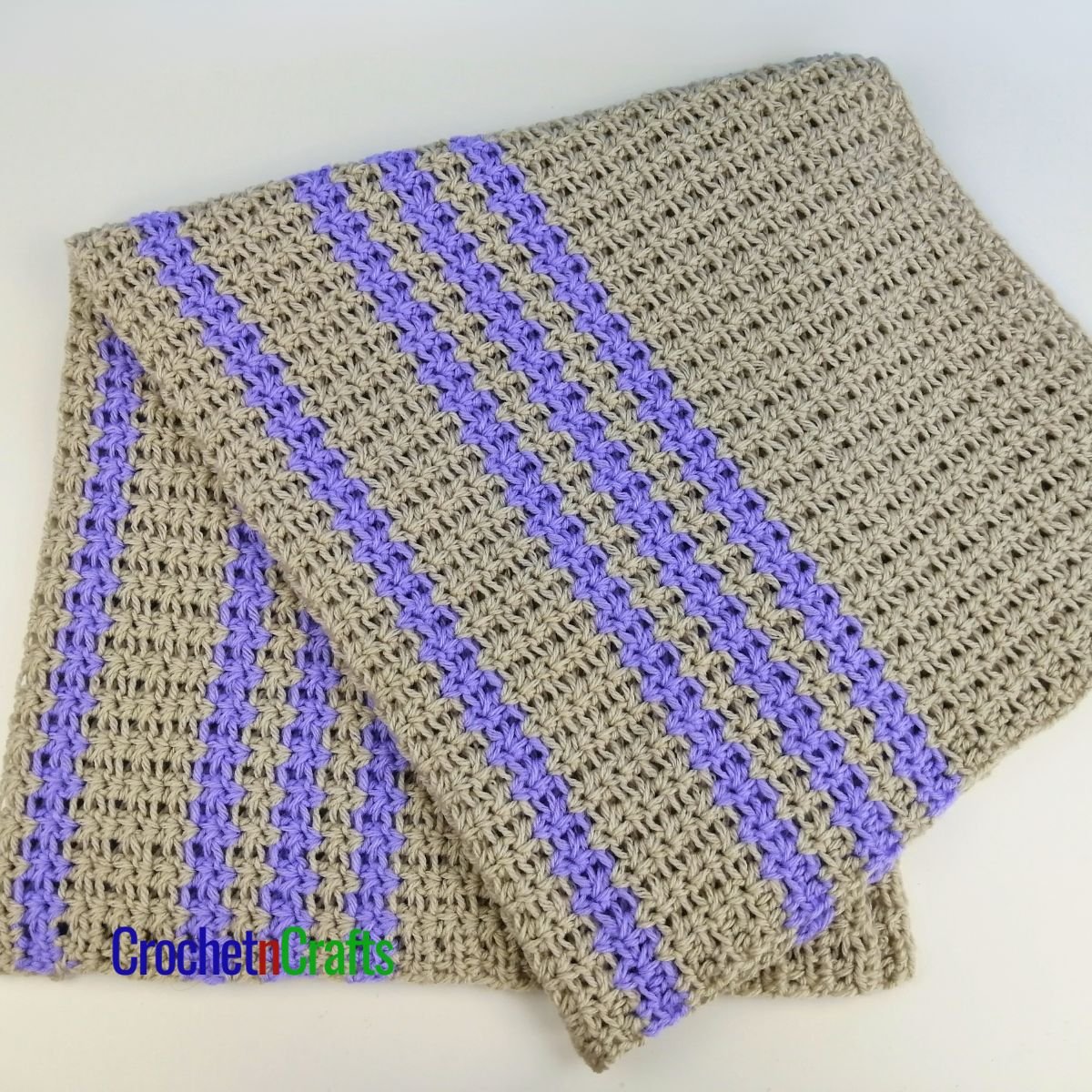 A crocheted baby blanket folded up.