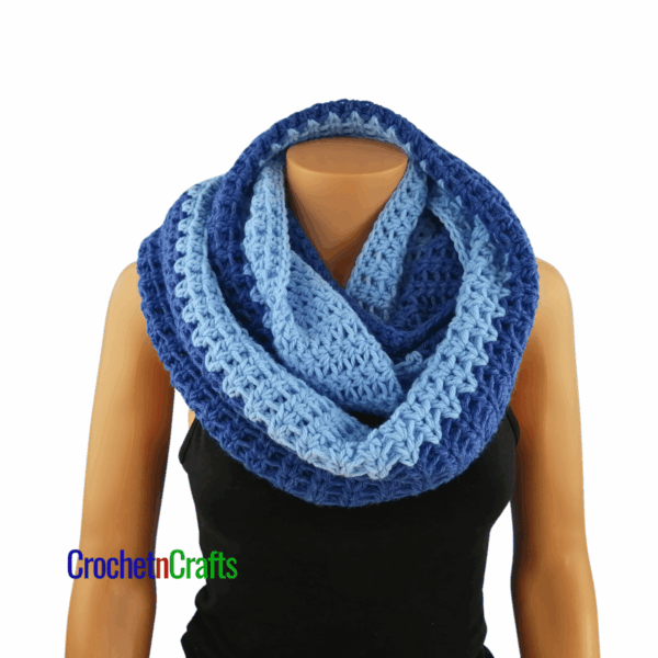 A crochet cowl wrapped cozy around the neck.