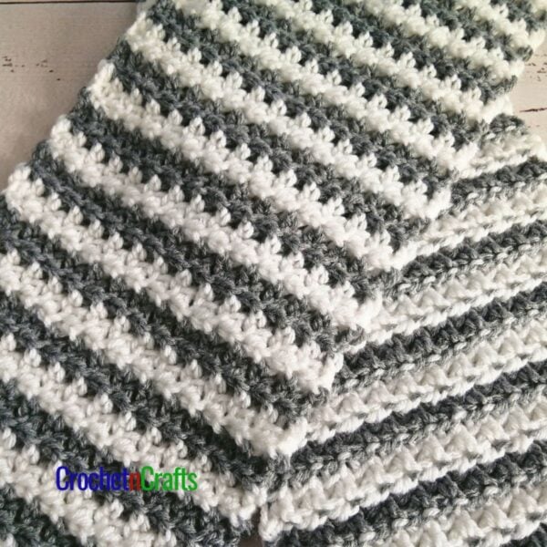 A striped crochet scarf laid flat and shown from both sides.