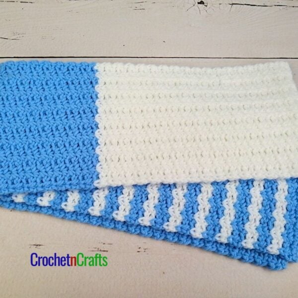 A crochet spider stitch scarf laid flat.