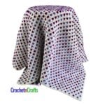 A crocheted lapghan draped over a stool.