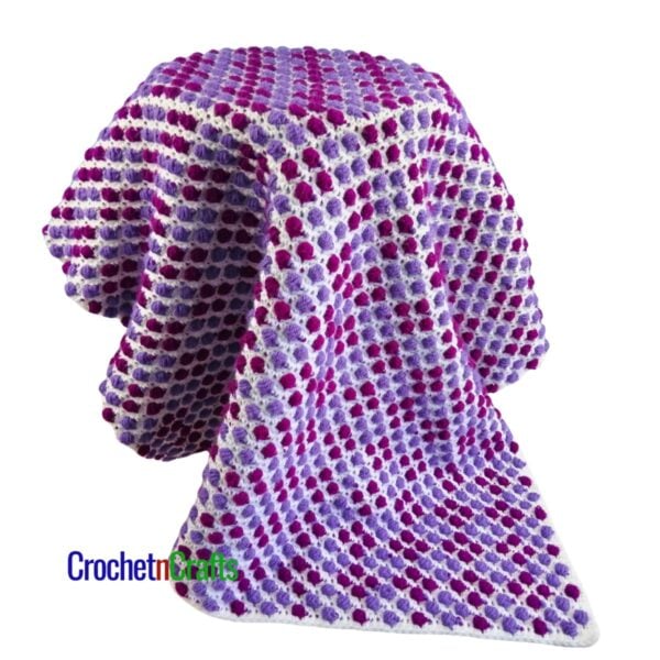 A crocheted lapghan draped over a stool. The side shown pops with color.