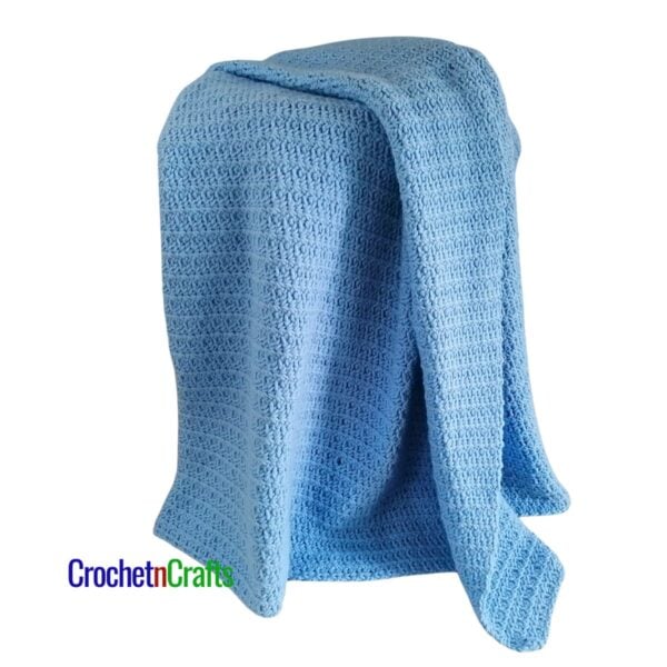 A simple crocheted blanket draped over a stool.