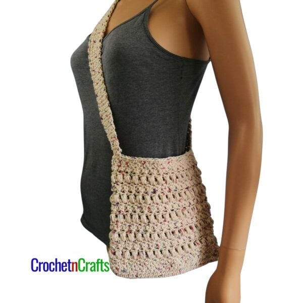 A small crocheted bag worn as a cross-body bag.