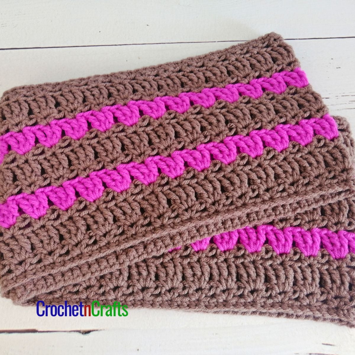 A striped crochet cowl laid flat.