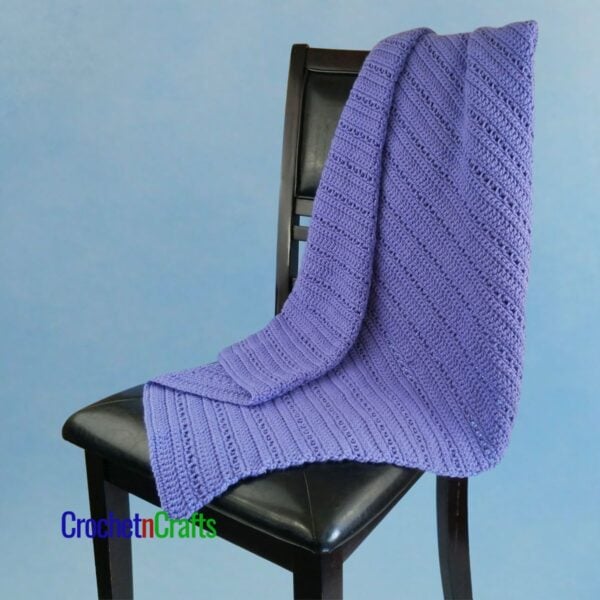 A crocheted lapghan draped over the back of a chair.