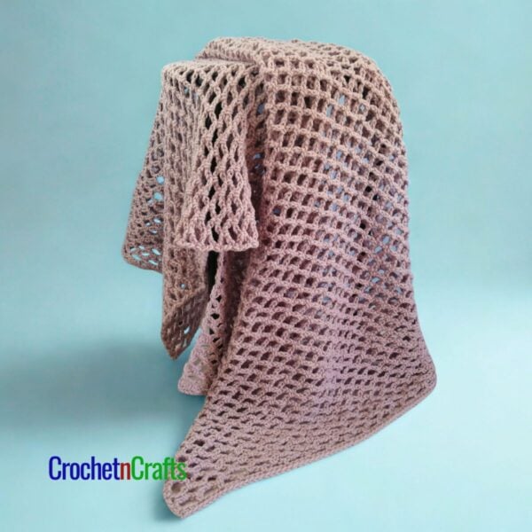 A crocheted mesh blanket draped over a stool.