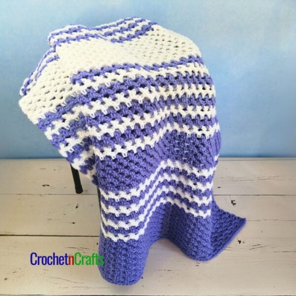 A striped mesh blanket is draped over a stool.