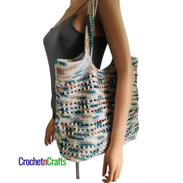 Crochet tote bag draped over the shoulder of a mannequin.
