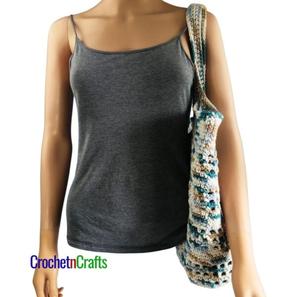 Crochet tote bag draped over the shoulder of a mannequin.