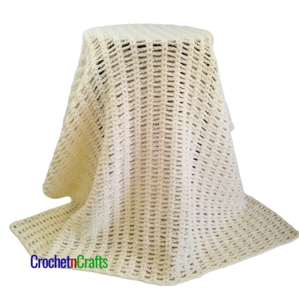 A crocheted blanket draped over a stool.