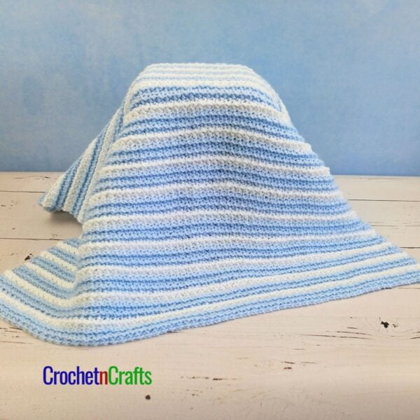 Striped Crochet Baby Blanket Draped Over a Child's Stool.