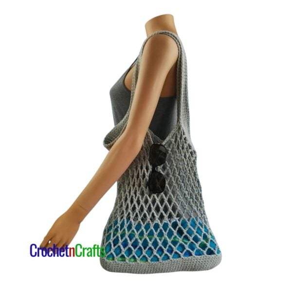 Crochet Mesh Bag Pattern Draped over the shoulders of a Mannequin.